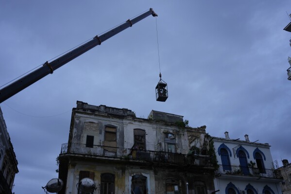 A crane lifts firefighters in a cage toward a building in search of survivors after it partially collapsed in Havana, Cuba, Wednesday, Oct. 4, 2023. (AP Photo/Ramon Espinosa)