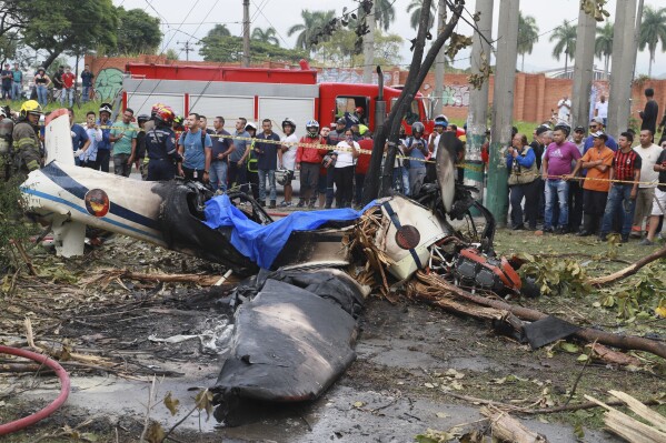 Residents looks at the wreckage of a Colombian Air Force aircraft that crashed into an urban area of Cali, Colombia, Tuesday, Oct. 3, 2023. According to authorities, one person on board died and another survived. (AP Photo/Juan B. Diaz)