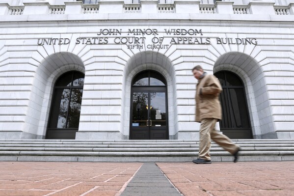 FILE - A man walks in front of the 5th U.S. Circuit Court of Appeals in New Orleans, Jan. 7, 2015. A federal judge's plan to hold hearings the first week of October 2023 to draw up congressional boundary lines that would give Louisiana a second majority-Black district has been blocked by an appeals court. (AP Photo/Jonathan Bachman, File)