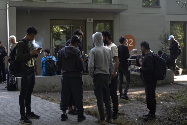 Dozens of people from all over the world line in front of the central registration center for asylum seekers in Berlin, Germany, Monday, Sept. 25, 2023. Across Germany, officials are sounding the alarm that they are no longer in a position to accommodate migrants who are applying for asylum. (AP Photo/Markus Schreiber)