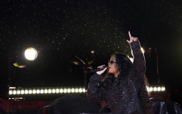 H.E.R. performs in rain during her opening set for Coldplay at the Rose Bowl, Saturday, Sept. 30, 2023, in Pasadena, Calif. (AP Photo/Chris Pizzello)