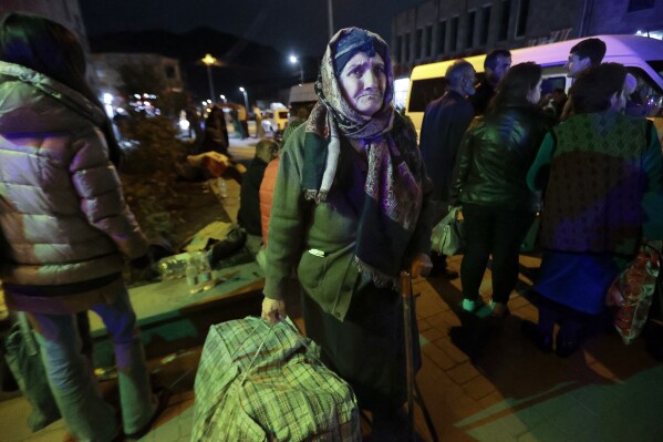 An ethnic Armenian woman from Nagorno-Karabakh carries her suitcase to a tent camp after arriving to Armenia's Goris in Syunik region, Armenia, late Friday, Sept. 29, 2023. Armenian officials say that by Friday evening over 97,700 people had left Nagorno-Karabakh. The region's population was around 120,000 before the exodus began. (AP Photo/Vasily Krestyaninov)